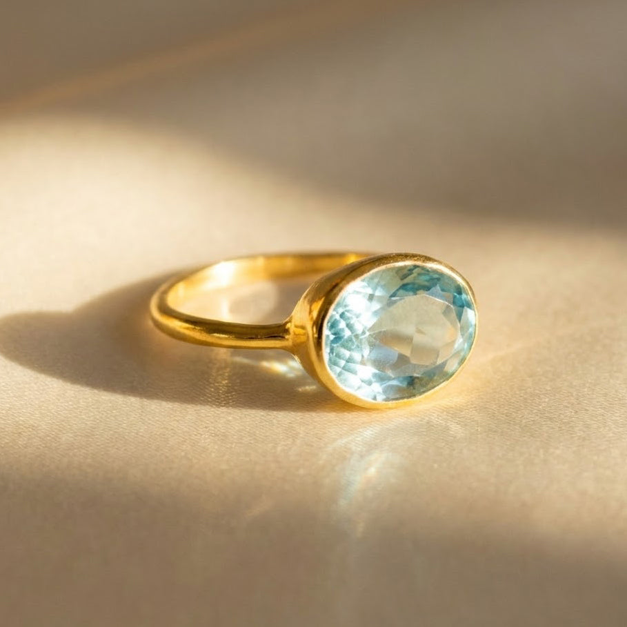 Oval blue topaz ring in gold bezel setting featuring faceted December birthstone gemstone, dainty oval gemstone ring for women in yellow gold vermeil, minimalist everyday stacking birthstone jewelry