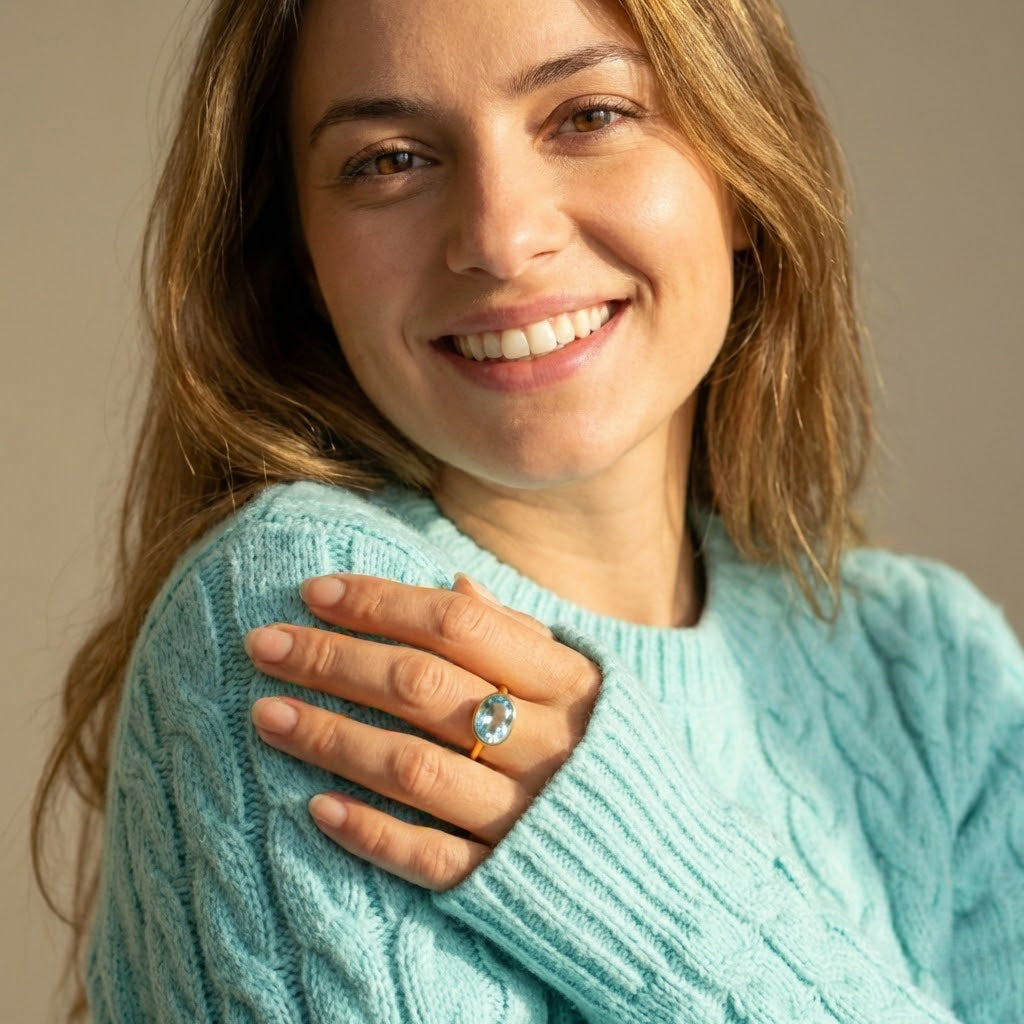 Blue topaz ring December birthstone worn by model, oval gold gemstone ring for women, minimalist dainty jewelry styled for everyday wear