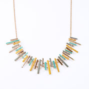 Adjustable Rose Gold Plated Necklace with a cable chain and connected pendants with vertical bars of varying lengths painted in teal, gray, and gold enamel against a white background