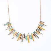 Adjustable Rose Gold Plated Necklace with a cable chain and connected pendants with vertical bars of varying lengths painted in teal, gray, and gold enamel against a white background