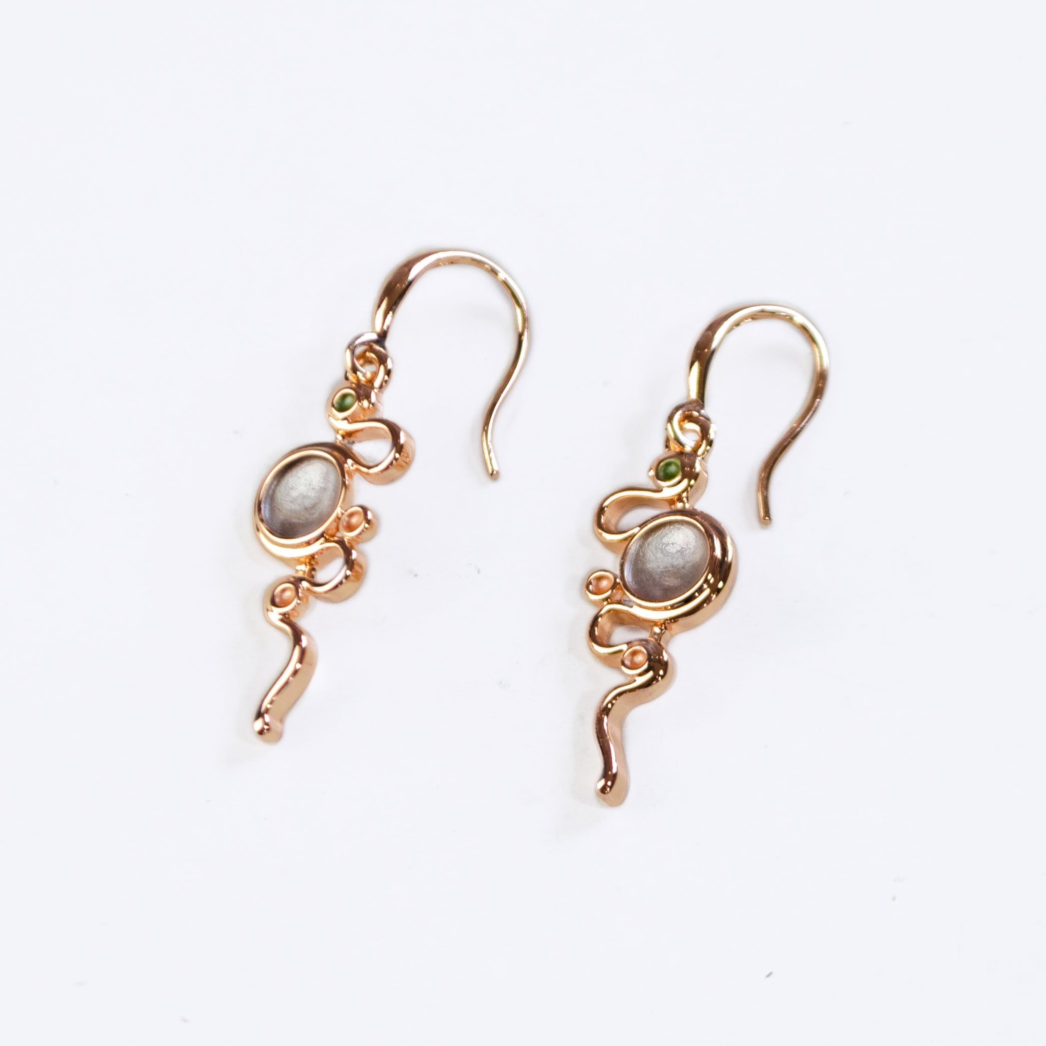 Rose Gold Plated Dangle Earrings  on a white background with a hook back and a thin rose gold serpent snaking around three small circles and one large circle each painted in green, gray, and gold enamel