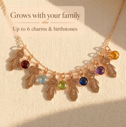 Family necklace with up to six child charms and birthstones shown on warm neutral fabric.