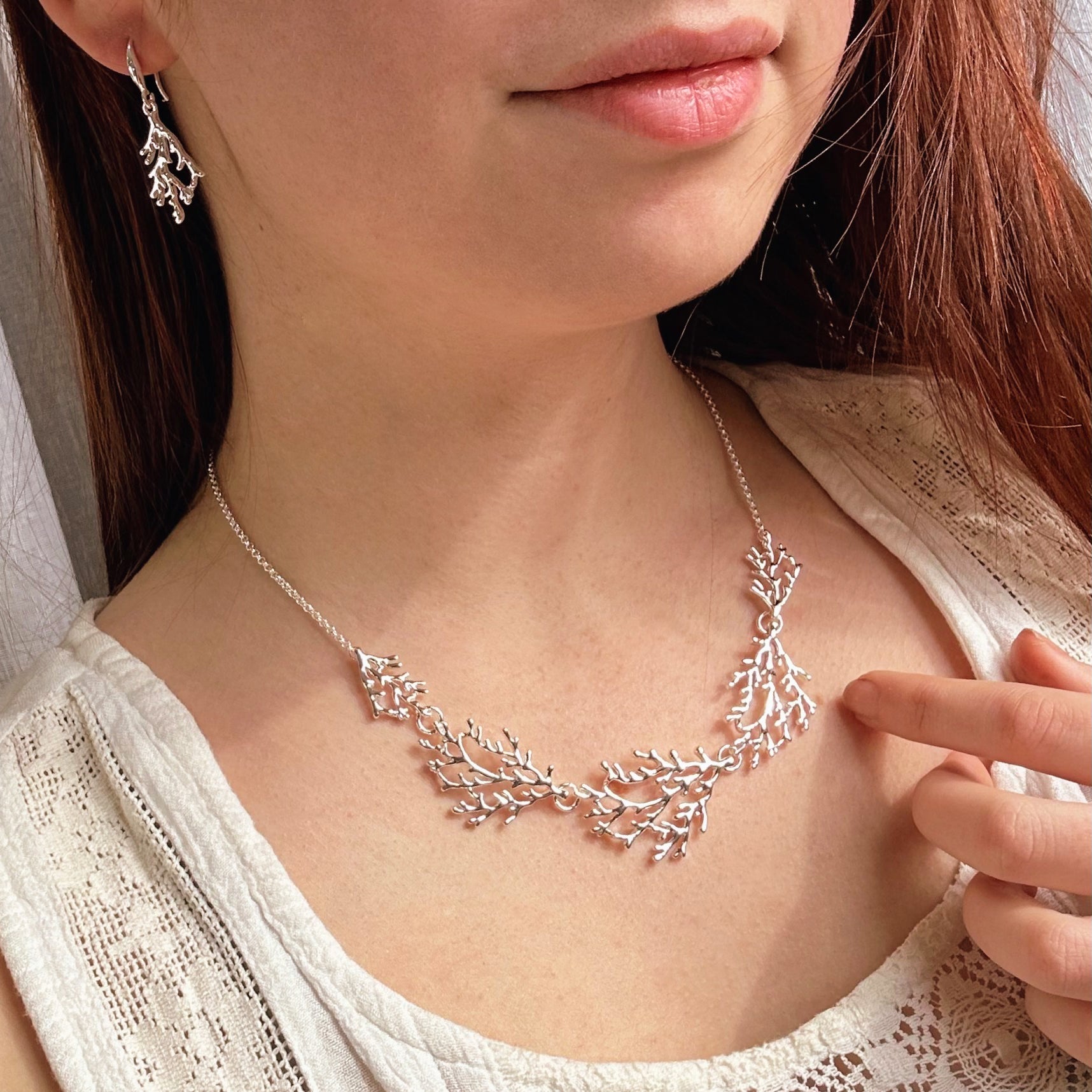 Model wears matching silver branch earrings and necklace