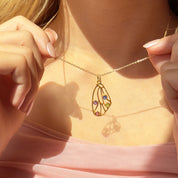 Gold butterfly wing necklace with colorful birthstone charms on model’s neck, personalized memorial jewelry gift for her, dainty nature inspired pendant close up