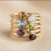 Custom family birthstone ring stack with colorful oval gemstones in a gold bezel setting