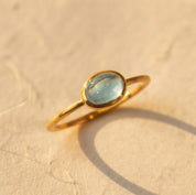 December blue topaz oval cabochon gemstone ring in a yellow gold bezel setting
