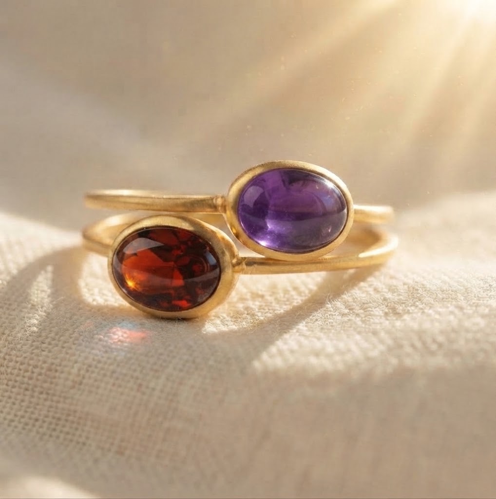 Stackable oval cabochon birthstone rings with garnet and amethyst gemstones in yellow gold bezel settings