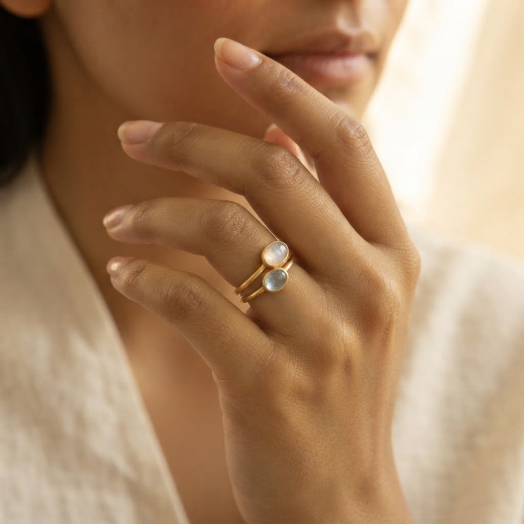 Woman wearing delicate oval cabochon birthstone rings in a minimalist gemstone ring stack