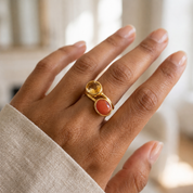 Oval carnelian and citrine gemstone rings stacked on a woman’s hand, showing coordinating faceted stones and gold bezel settings.