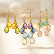 Custom mother’s birthstone earrings featuring teardrop gemstones personalized to represent children or grandchildren, handcrafted in sterling silver or gold filled metal as meaningful family jewelry for Mother’s Day or birthdays.