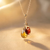 Personalized family birthstone necklace with teardrop gemstones and initial charms in gold
