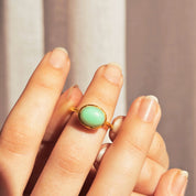 Model with a french manicure wears a vermeil gold plated sterling silver oval solitaire ring bezel set with natural mint green ChrysopraseTurquoise Statement Ring, Spring Ring