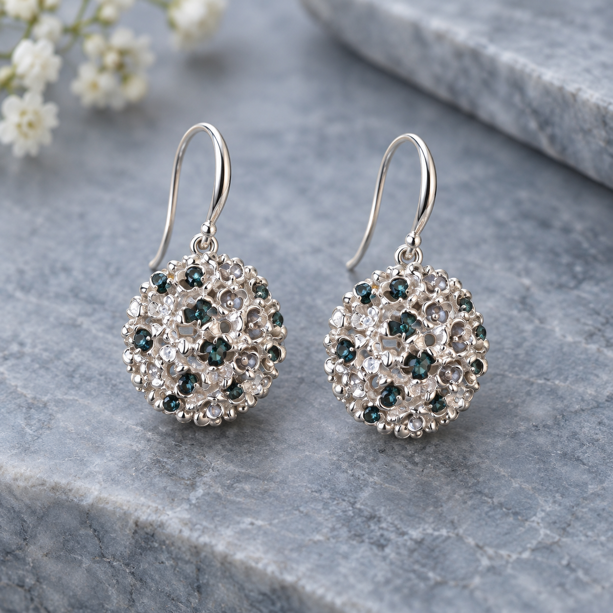 Constellation Orb statement earrings with sparkling aqua accents displayed on gray stone

