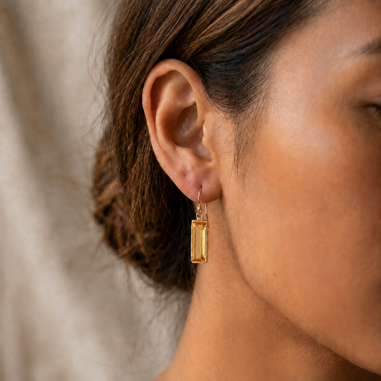 Close-up of a woman wearing a golden Citrine Quartz bar drop earring
