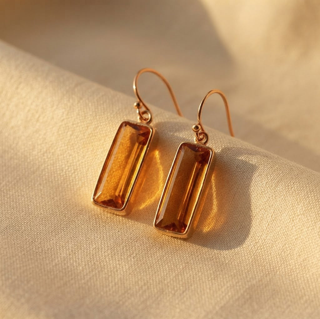 Citrine Quartz baguette earrings casting warm shadows on cream fabric