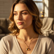 Model in beige top is wearing a prong teardrop citrine birthstone necklace with a classic initial engraved. November birthstone, december jewelry, blue stone, blue birthstone