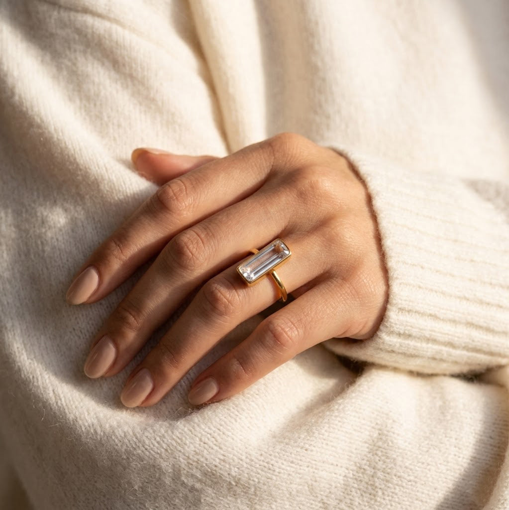 Hand wearing clear quartz bar ring, minimalist gold stacking ring with crystal gemstone

