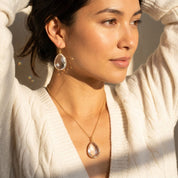 clear quartz drop earrings gold dainty april birthstone earrings on model