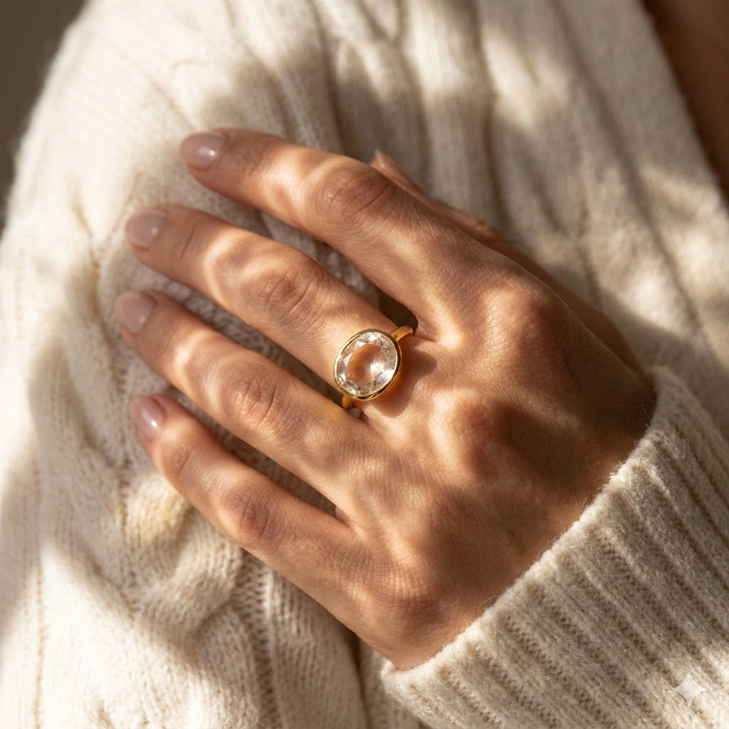 Woman wearing oval clear quartz ring in gold, dainty statement ring with faceted gemstone