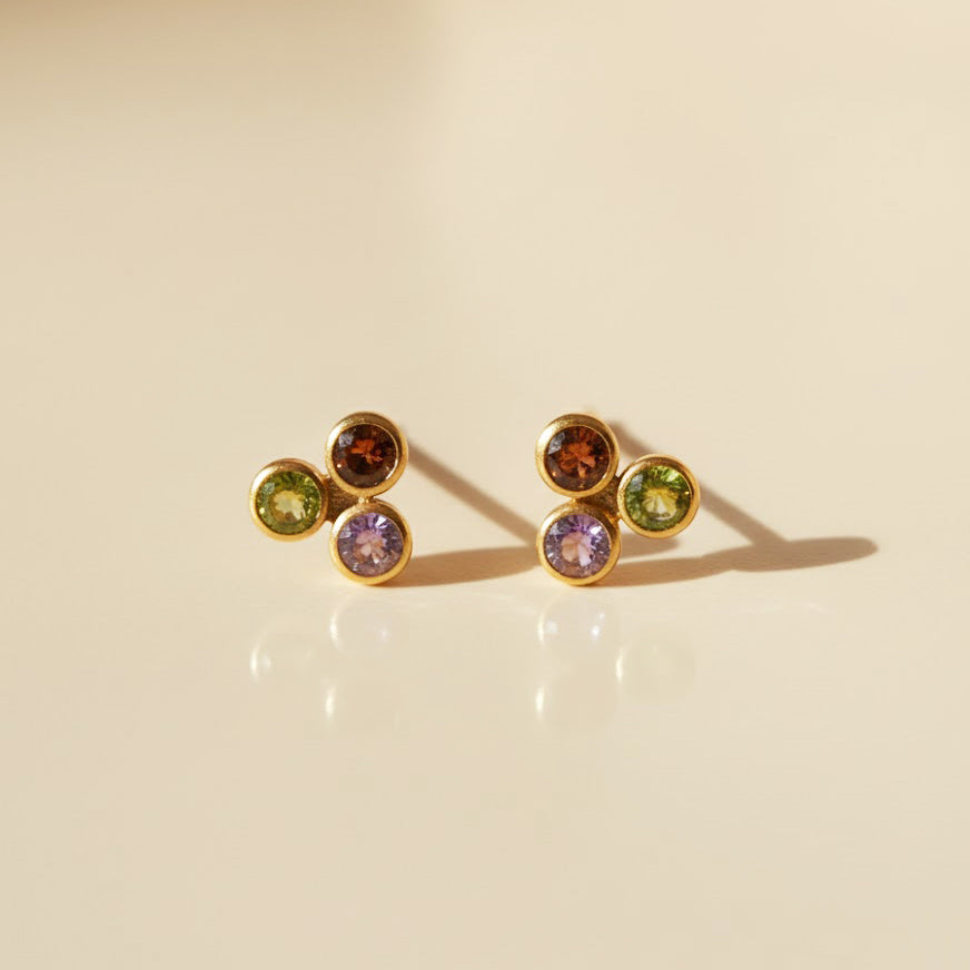 Cluster birthstone bar stud earrings showcased close-up on a cream surface, featuring dainty bezel-set gemstones in vibrant birthstone colors. Crafted in .925 sterling silver or 18k gold vermeil, these minimalist multi-stone studs make thoughtful birthday gifts, mom jewelry, bridesmaid gifts, or keepsake personalized earrings. Elegant, meaningful gemstone design perfect for daily wear.