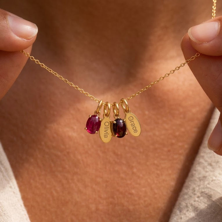 Personalized Mom birthstone necklace with oval gemstone charms and engraved children's name tags in yellow gold.
