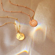 Romantic rose gold constellation necklaces photographed on satin, luxe engraved disc pendants that layer beautifully. Spotlight Aries, Leo, Sagittarius fire-sign gifting with month cues March–April, July–August, November–December. Custom text on the reverse, adjustable lengths, minimalist style for stacking with other pendants. Thoughtful birthday, anniversary, or Christmas gift for astrology lovers and bridesmaids.
