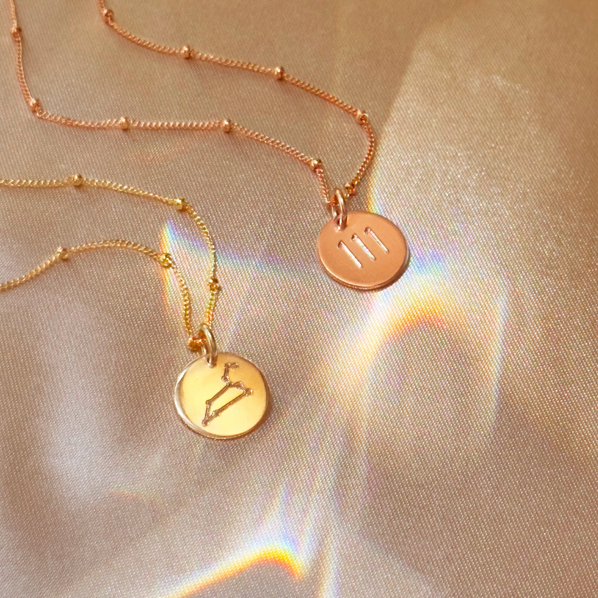 Romantic rose gold constellation necklaces photographed on satin, luxe engraved disc pendants that layer beautifully. Spotlight Aries, Leo, Sagittarius fire-sign gifting with month cues March–April, July–August, November–December. Custom text on the reverse, adjustable lengths, minimalist style for stacking with other pendants. Thoughtful birthday, anniversary, or Christmas gift for astrology lovers and bridesmaids.