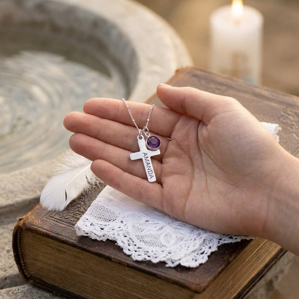 Hand holding engraved cross necklace with birthstone charm, personalized baptism or confirmation gift necklace