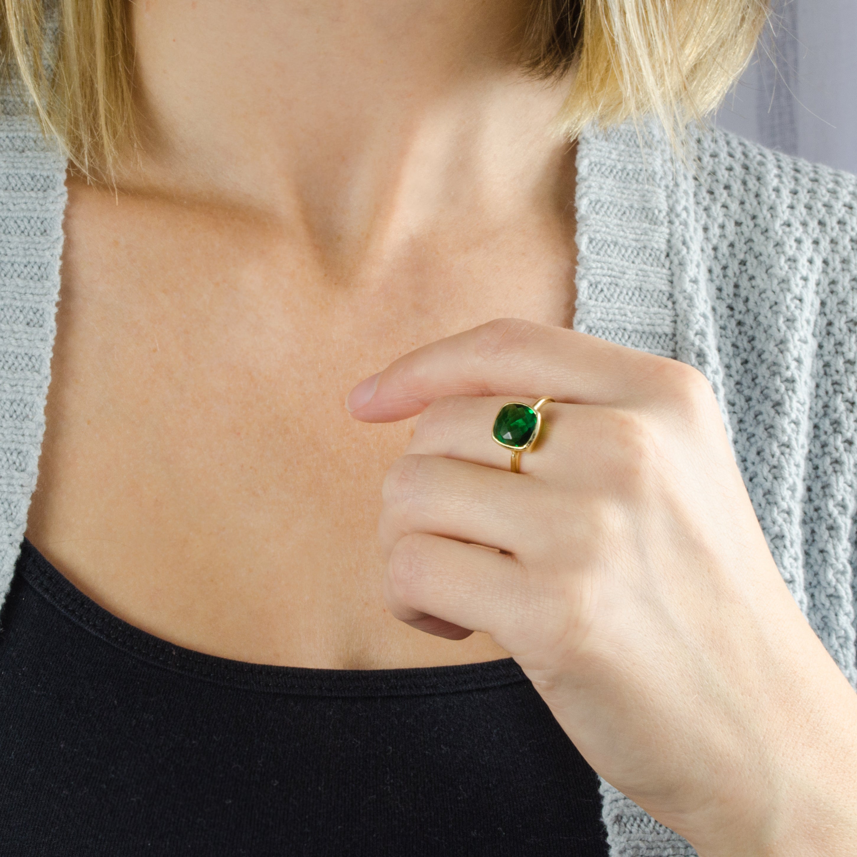 A model wearing a  Natural Birthstone cushion bezel ring with Green Emerald. These rings are available in Garnet, Purple Amethyst, Aquamarine, Clear Quartz, Emerald, Moonstone, Ruby, Sapphire, Fire Opal, Blue Topaz. Ready for gift giving in Danique Jewelry Branded Box. Available in Yellow or Rose gold or in Sterling Silver