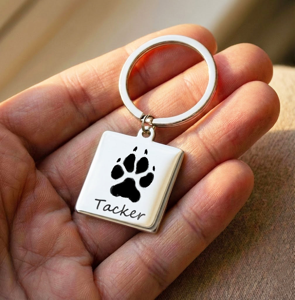 Custom pet paw print keychain engraved with dog name, shown held in hand to highlight detailed paw engraving and polished stainless steel finish. This personalized paw print keychain makes a meaningful dog memorial gift, sympathy gift for pet loss, or everyday keepsake for dog lovers. Ideal for dog moms, pet owners, and anyone wanting a custom pet accessory that honors a beloved companion with lasting quality and sentimental value.