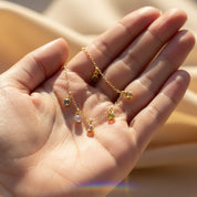 Hand holding delicate birthstone charm bracelet, tiny dangling gemstones on fine chain, personalized jewelry gift for her, Valentine’s Day or birthday present