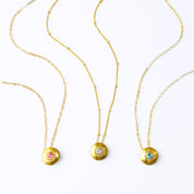 Three Necklaces with Bezel Set Round Pendants. Pendants are 18k Vermeil Gold with 14k Gold Filled Chains. From Left to Right: Ruby Quartz Pendant on a cable chain, Rainbow Moonstone Pendant on a Satellite Chain, Blue Topaz Pendant on a cable chain