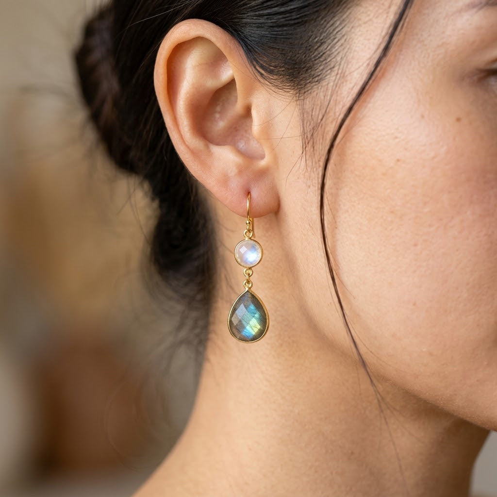 Woman wearing gold moonstone and labradorite double drop birthstone earrings.