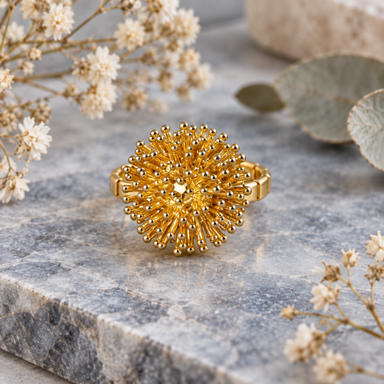 Gold Dandelion Puff statement ring displayed on light stone with botanical styling