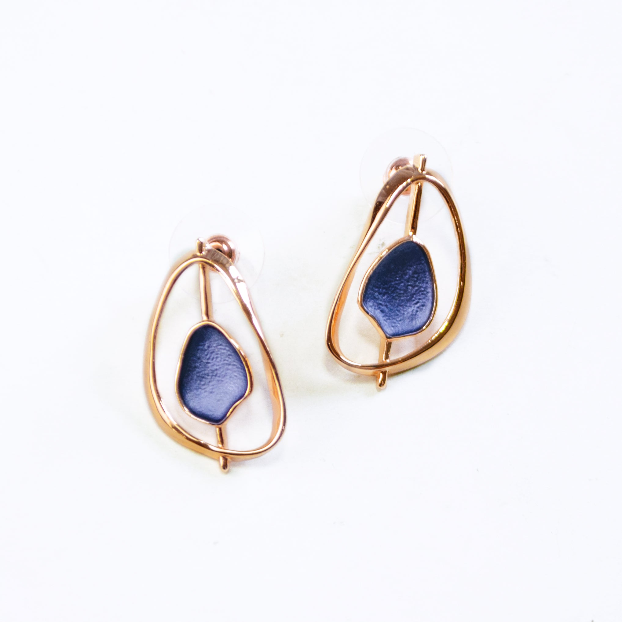 Open Pear shape rose gold stud earrings with a floating textured disc center painted in blue enamel on a white background