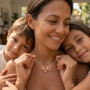 Mother with two children wearing a personalized gold circle birthstone necklace representing her family.
