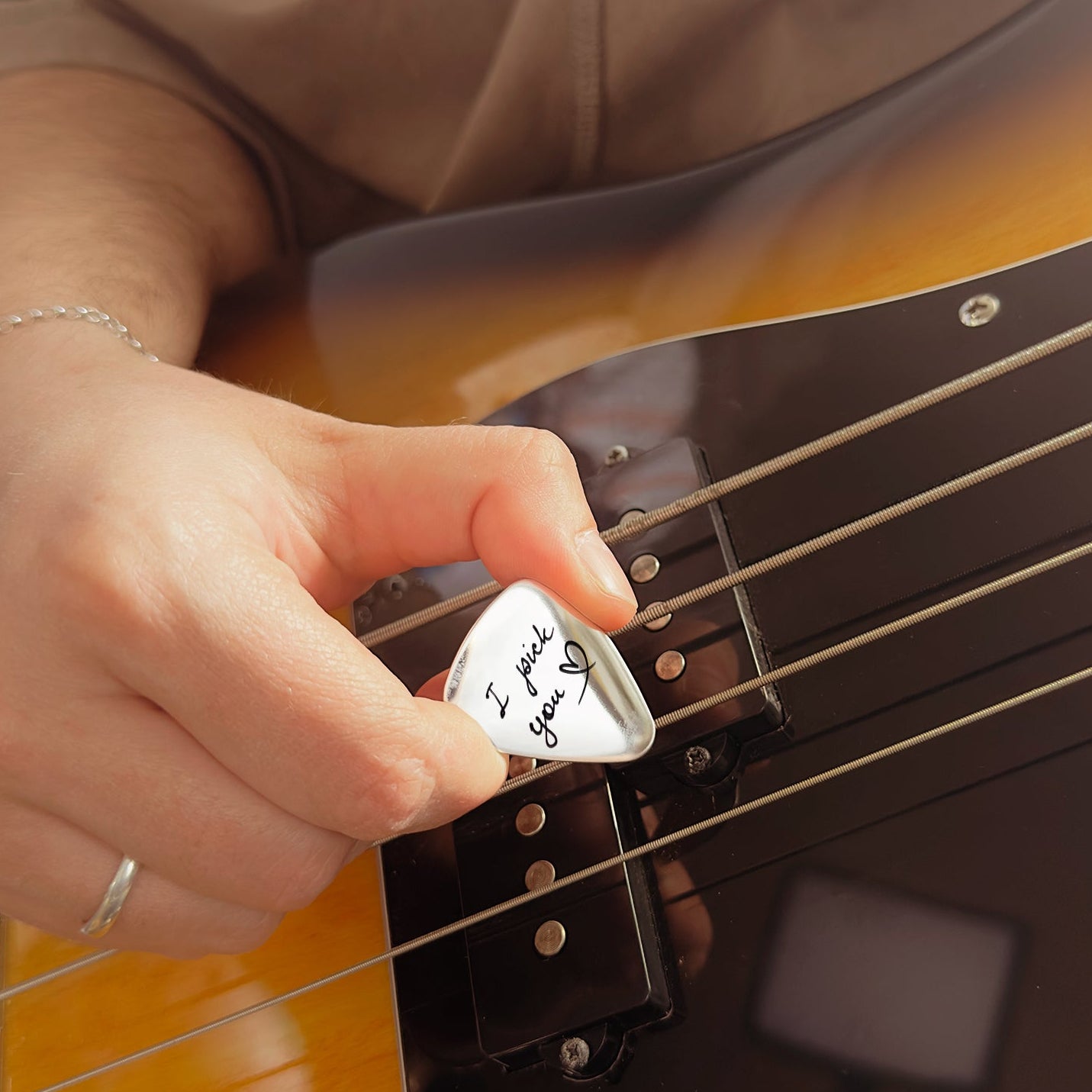 Musician playing bass guitar using custom engraved guitar pick, showing personalization in action and highlighting this as a practical and sentimental gift for music lovers.