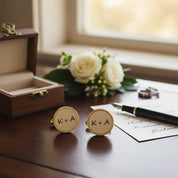 Custom engraved leather cufflinks with K + A initials in gold bezel, displayed on wedding desk with ring box, roses and invitation, personalized monogram cufflinks for groom or groomsmen, romantic anniversary or wedding day gift for him.