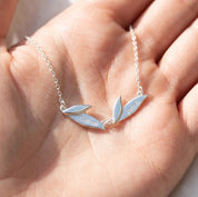 Sterling silver personalized leaf necklace shown in hand, featuring engraved leaf charms for a custom family keepsake necklace.