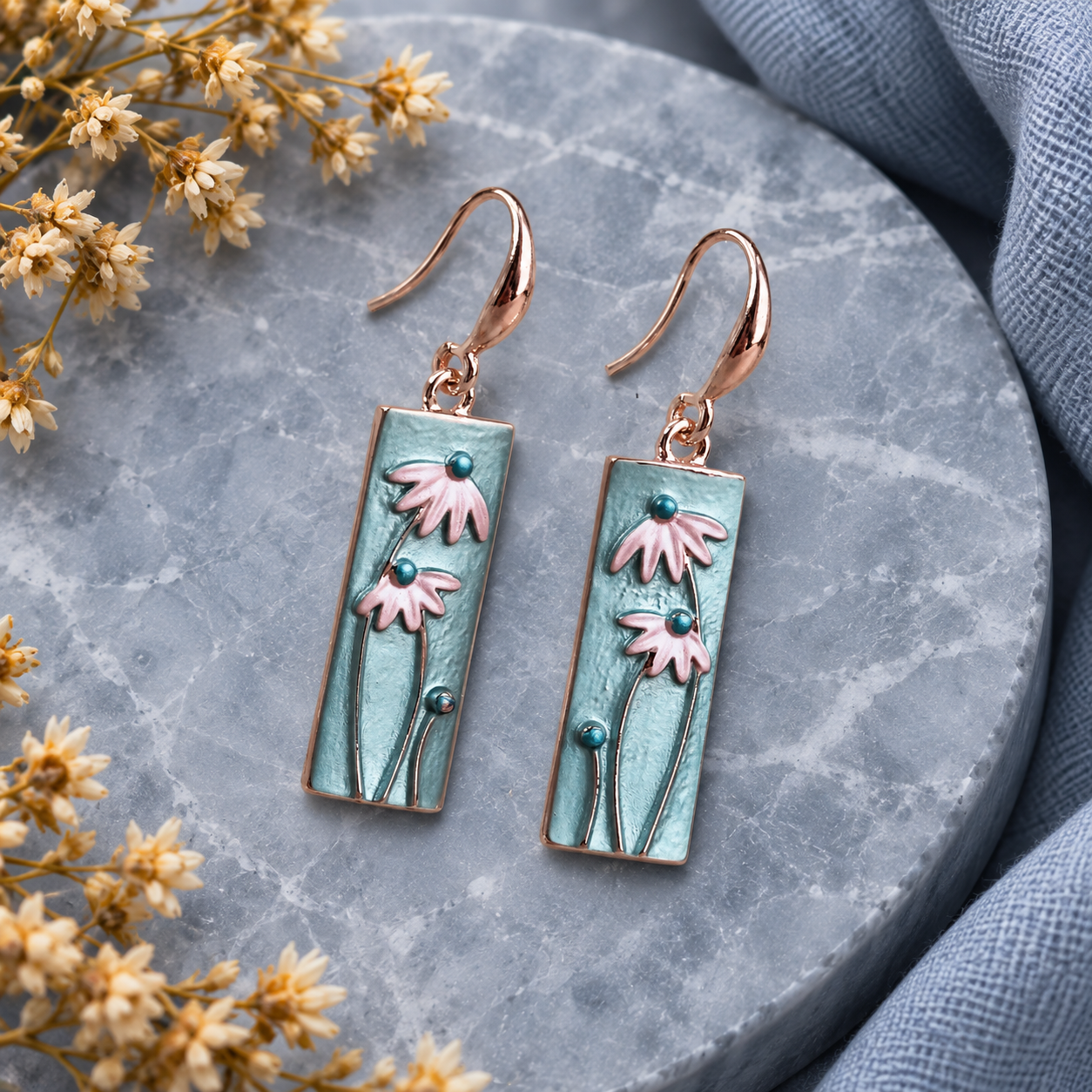Close up of rectangular floral dangle earrings with raised pink flowers
