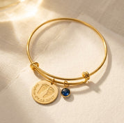 Personalized baby footprint birthstone bangle bracelet with engraved name and date, a meaningful new mom keepsake bracelet in gold.