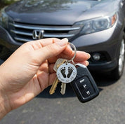Personalized baby footprint keychain attached to car keys, showing everyday use of an engraved baby footprint keepsake made from stainless steel. This custom baby footprint keychain transforms a real baby footprint into wearable jewelry, making it a meaningful gift for new moms or grandmas who want a daily reminder of their child or grandchild.