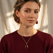 Woman wearing garnet teardrop earrings with matching January birthstone necklace
