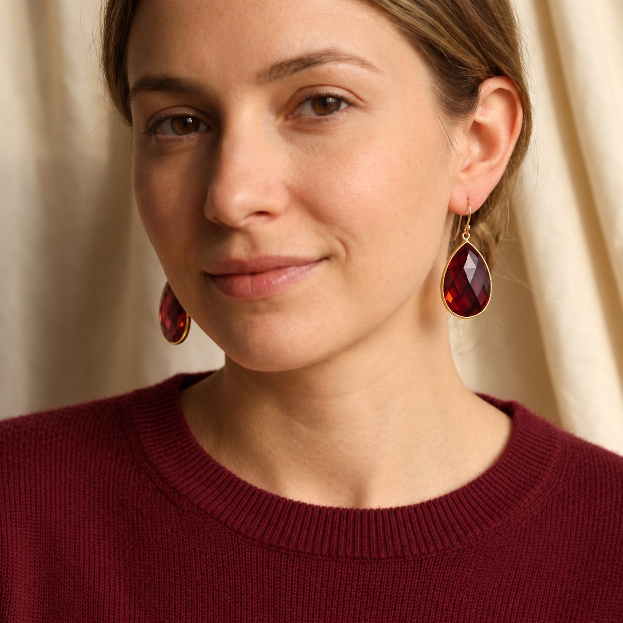 Woman wearing large garnet teardrop earrings in yellow gold
