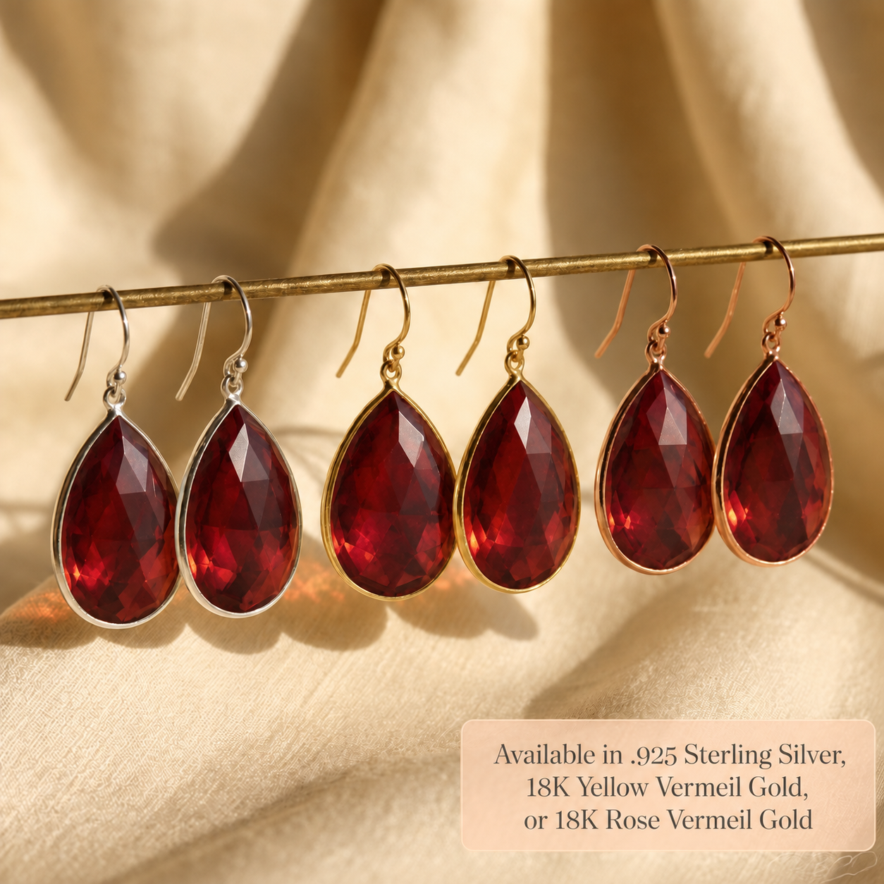Large garnet teardrop earrings displayed on jewelry stand in sterling silver, yellow and rose gold
