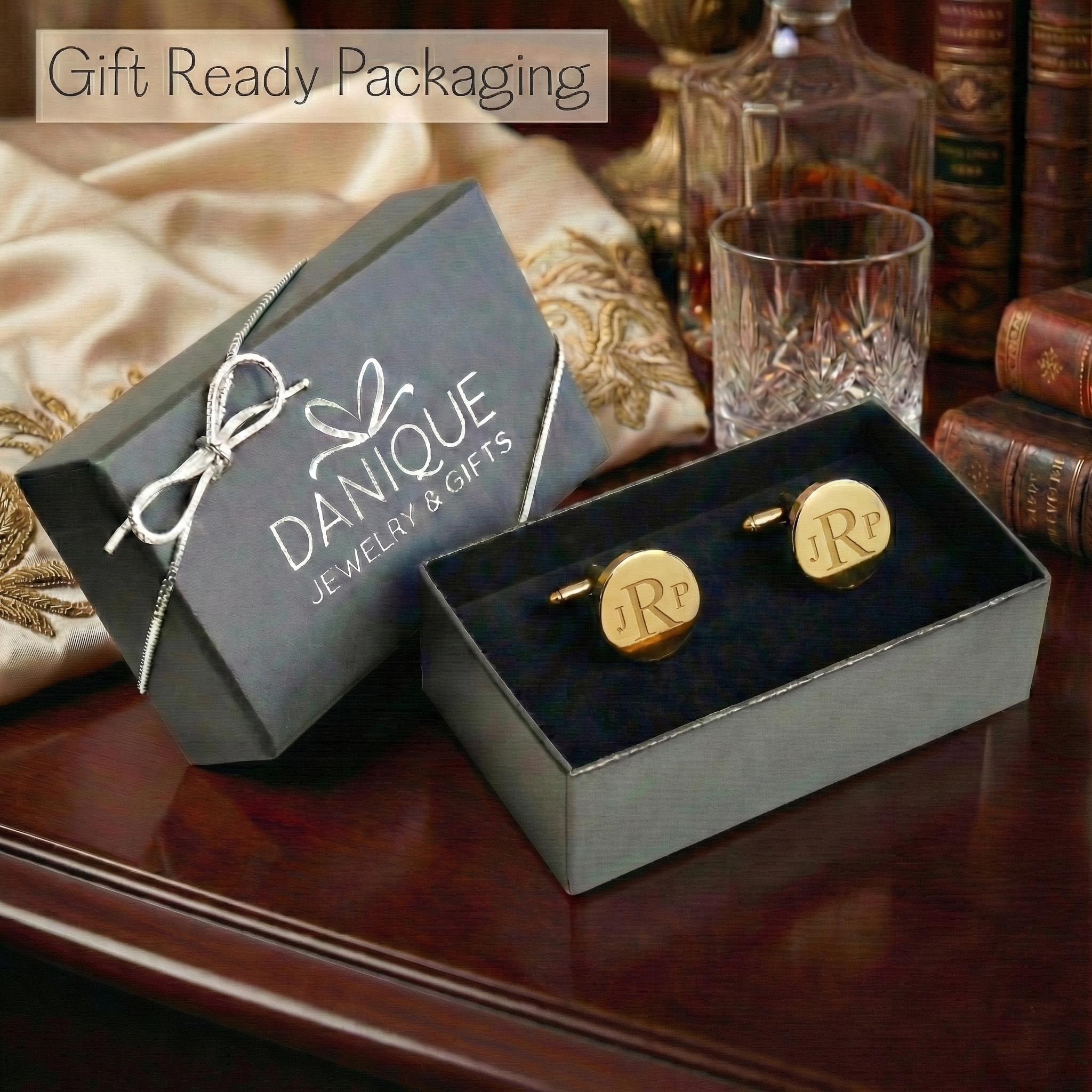 Gold cufflinks in a box with 'DANIQUE' packaging on a wooden surface. Engraved stainless steel cufflinks presented in a signature gift box, personalized with a name or date for a refined and memorable Father’s Day, wedding, or anniversary gift that blends timeless style with heartfelt meaning.