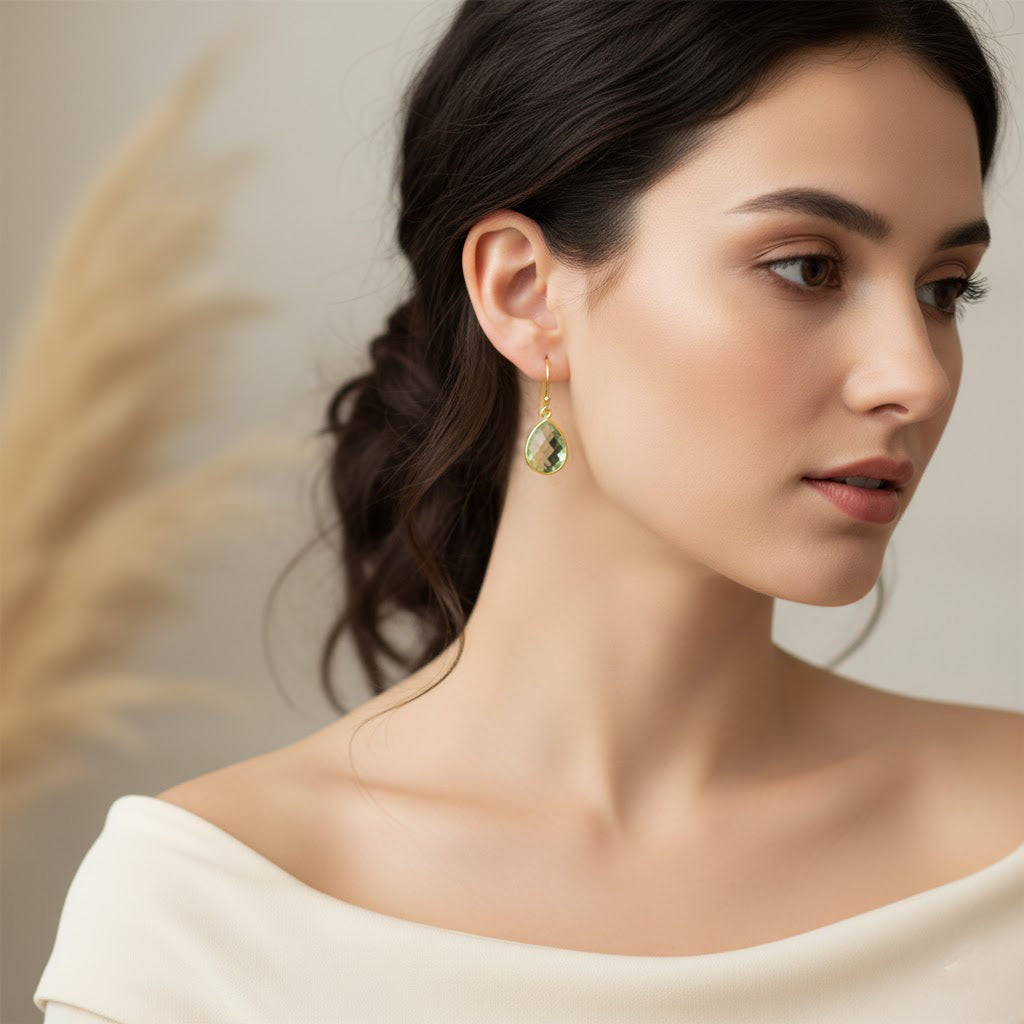 Woman wearing green amethyst drop earrings in gold setting, faceted teardrop prasiolite gemstone earrings, elegant minimalist jewelry for everyday wear.