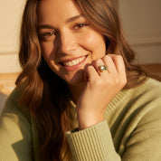 Close-up portrait of woman wearing cushion cut green amethyst ring in polished gold bezel setting, February birthstone prasiolite gemstone glowing softly, square sage green gemstone ring, minimalist fine jewelry, dainty stacking gold ring, elegant handcrafted birthstone jewelry for women