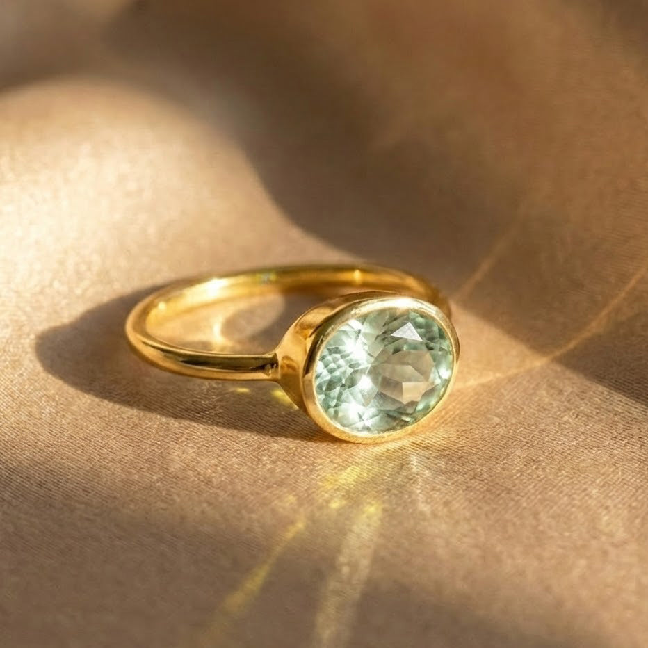 Green amethyst oval bezel set ring in 18K gold vermeil, minimalist February birthstone ring photographed on neutral fabric, dainty gemstone ring for women, elegant everyday jewelry gift