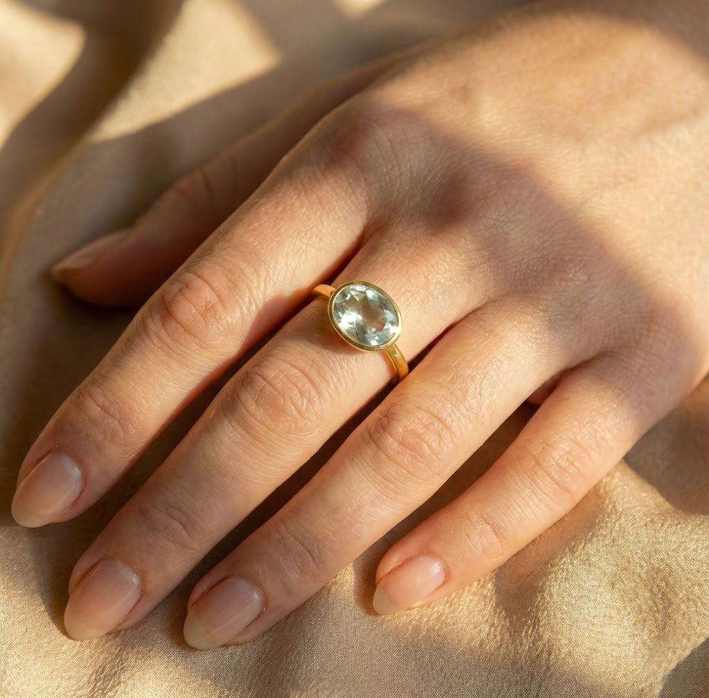 Green amethyst February birthstone ring worn on finger, oval bezel set gemstone ring in gold, elegant minimalist jewelry designed for everyday wear
